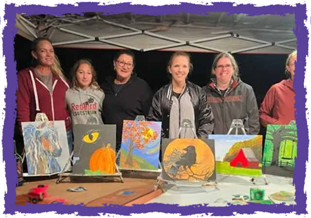 A group of people standing around some paintings