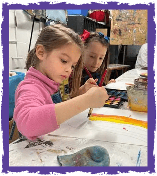 Two young girls painting on a table.