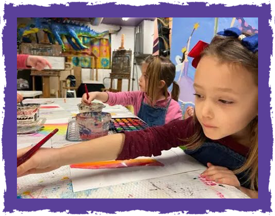 A girl is painting with her hands on the table.