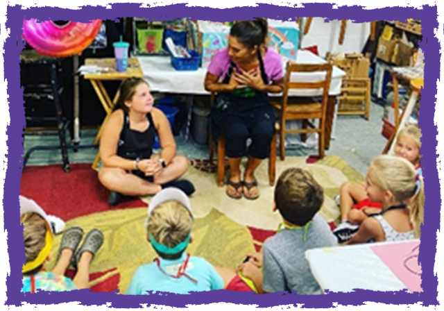 A group of children sitting around in front of an adult.