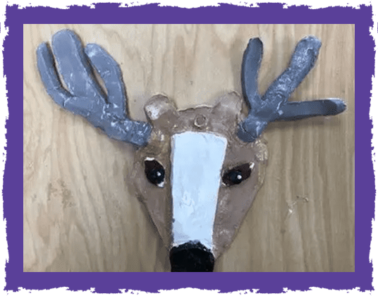 A paper mache deer head on top of a wooden table.