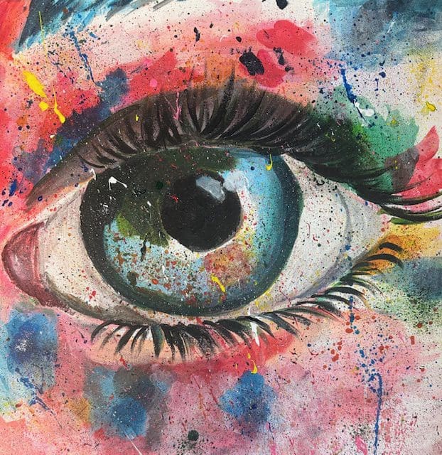 A close up of an eye with colorful paint splashing all over it.